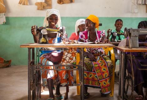 Two women working at sewing machines and smiling