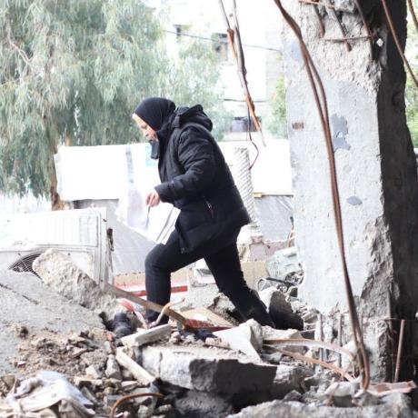 A lady walking through rumble of destroyed building in Gaza